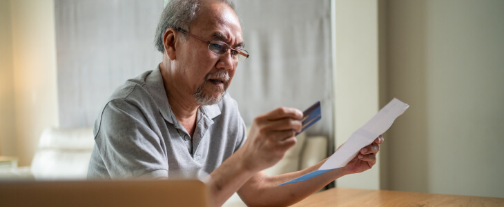 A man looks at credit card and statement worried