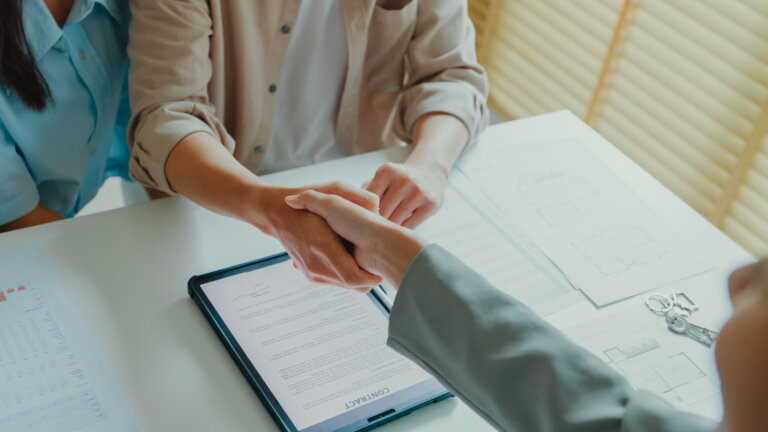 Close-up of tenants sign house agreements on tablet and give them to female real estate agent after showing new houses. Landlord selling real estate to customers for investment concept.