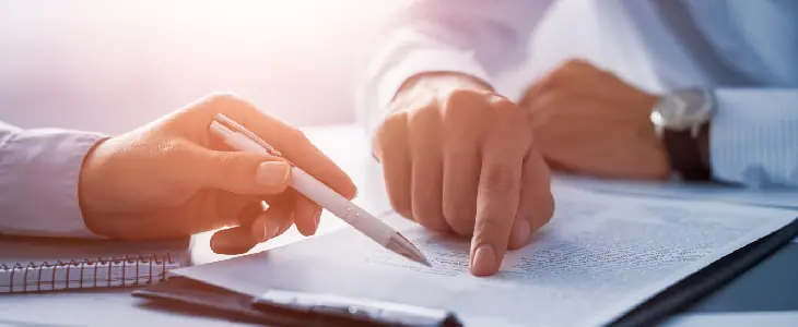 two professionals looking over a document on a clipboard holding a pen business law