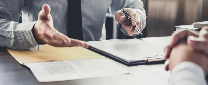 Close-up of a business discussion with documents and a pen on a desk.