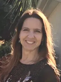 Happy woman posing in natural light with a blurred outdoor background.