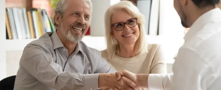 An older couple shakes hands with an attorney